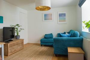 sala de estar con silla azul y TV en Pebbles, en Lyme Regis
