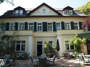 Hotel & Restaurant Bellevue Schmölln في Schmölln: منزل كبير أمامه طاولات وكراسي