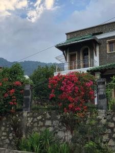 uma casa com flores vermelhas numa varanda em Marie'z Villa em Tuk Tuk