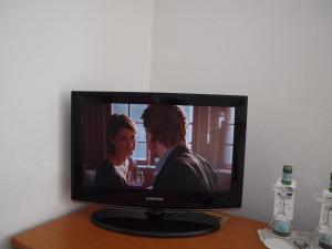 a television with a picture of a man and a woman at Hotel & Restaurant Bellevue Schmölln in Schmölln