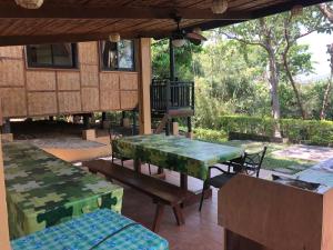 a patio with green tables and benches on a house at Native House with beautiful pool in Bagac