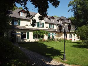 a large white house with green shutters and a street light at Hotel & Restaurant Bellevue Schmölln in Schmölln