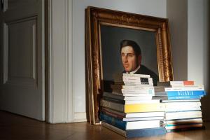a stack of books in front of a portrait of a man at 0.3 Stanze in Trieste