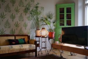 a living room with a tv and a couch and plants at 0.3 Stanze in Trieste