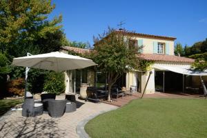 a patio with chairs and an umbrella and a house at Au pays de Cézanne Picasso & Matisse in Aix-en-Provence