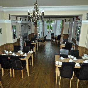 a restaurant with wooden tables and chairs and a chandelier at Alpine Lodge Guest House in Llanberis