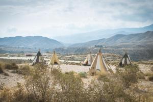un grupo de tiendas en el desierto con montañas en el fondo en Camping Fort Bravo, en Tabernas