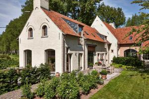 una casa blanca con techo naranja en De Zonnebrug Dijkhoeve, en Saint-Laureins