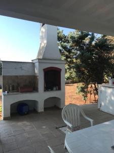 a fireplace on a patio with a table and a chair at Villa Brigida in Manduria