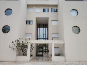 ein weißes Gebäude mit runden Fenstern und einer Treppe in der Unterkunft Cidade da Praia in Figueira da Foz