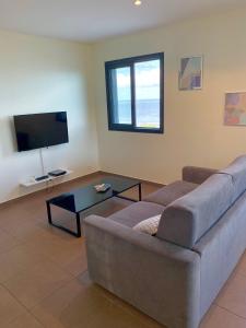 uma sala de estar com um sofá e uma televisão de ecrã plano em Bleu Horizon em Saint-Leu