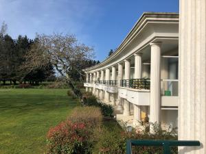 a white building with columns and a grass yard at SWING RESIDENCE GOLF LA BAULE in Saint-André-des-Eaux