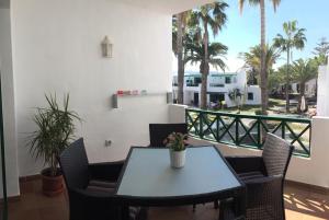 a table and chairs on a balcony with palm trees at Paradise Club L28 & L29 in Puerto del Carmen