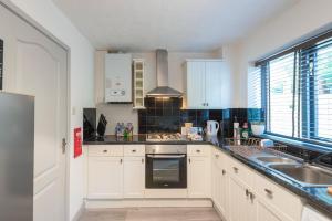 a kitchen with white cabinets and a sink at Snowdon Snug in Llanberis +21 photos