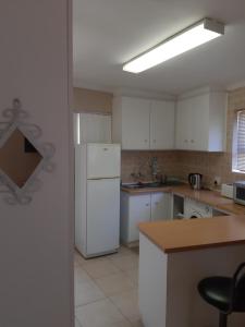 a kitchen with white cabinets and a white refrigerator at On Yonder Hill in Cape Town