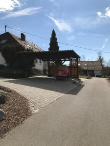 a red car parked under a shed in a driveway at Gästezimmer Süß- Scharf in Meckenbeuren