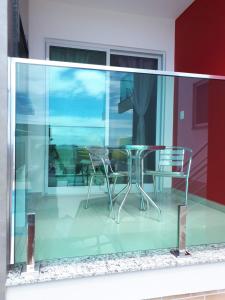 a glass balcony with a table and chairs at Beira Mar Village in Pinheira