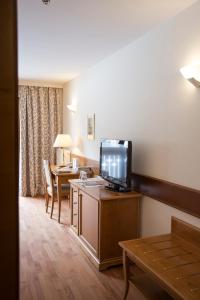 a hotel room with a television and a desk with a table at Parkhotel Tristachersee in Lienz