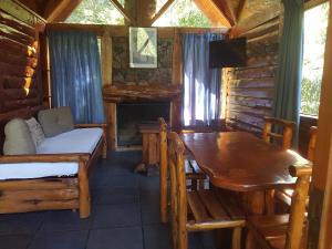 Cabaña de madera con mesa, cama y mesa de comedor en Cabañas Las Maras en Villa La Angostura