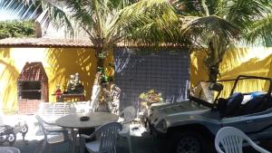 um pátio exterior com uma mesa e palmeiras em Praia Grande Surf Hostel em Arraial do Cabo
