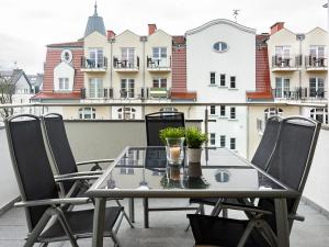 einen Tisch und Stühle auf einem Balkon mit einem Gebäude in der Unterkunft VacationClub – Stella Baltic Apartament 37 in Świnoujście