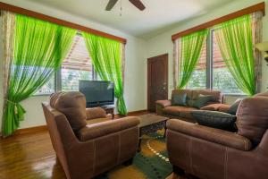 a living room with two chairs and a television at Los Olingos Lodge in Tela