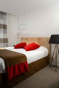 a bedroom with a large bed with red pillows at Hôtel Ar Iniz in Saint Malo