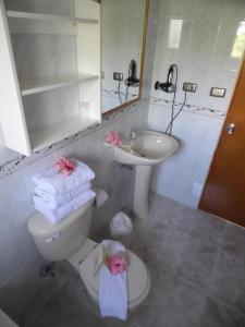 a bathroom with a toilet and a sink with towels at Hotel Manutara in Hanga Roa