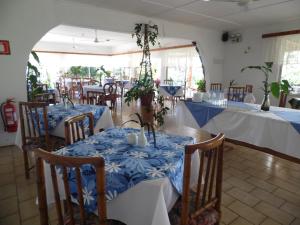 a dining room with tables with blue and white table cloth at Hotel Manutara in Hanga Roa