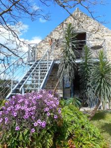 a stone house with a staircase and purple flowers at La grange aux lièvres, gîtes Kerdoel in Cléder