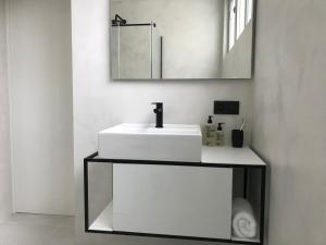a white sink sitting under a mirror in a bathroom at B&B Inn Between in Ghent
