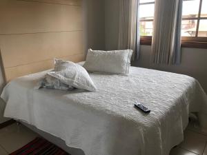 a bed with pillows and a remote control on it at Praia do Forte Luxuoso Village in Matta de São João +42 photos
