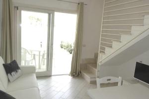 ein Wohnzimmer mit einer weißen Couch und einer Treppe in der Unterkunft Romantica casa al mare con piscina in Sardegna in Viddalba