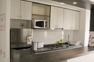 a kitchen with white cabinets and a stainless steel refrigerator at playa paraiso en Parque Surire in Arica