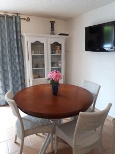 a dining room table with a vase of flowers on it at GITE LES PINS piscine chauffée jardin privatif climatisation Wifi parking in Peymeinade