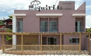 une maison rose avec une terrasse en bois devant elle dans l'établissement Pousada Moquirido, à Florianópolis
