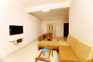 Castilo Inn Hotel Apartments في كوتشي: غرفة معيشة مع أريكة وتلفزيون