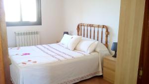 uma cama com lençóis brancos e almofadas num quarto em turismo rural del somontano (Alquiler de apartamentos) em Salas Bajas
