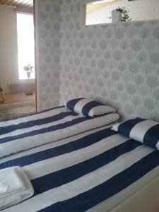 two beds with blue and white striped sheets in a bedroom at RBA RentHouse Apartment 2 in Nedervetil