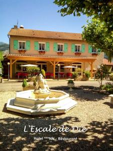 une statue devant une maison avec un bâtiment dans l'établissement L'Escale de Die, à Die