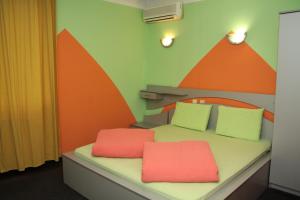 アセノヴグラトにあるHotel Colorの赤い枕2つが付いたベッド1台が備わる客室です。