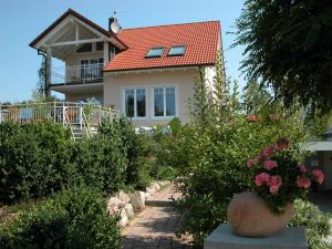 uma casa com um telhado vermelho e alguns arbustos em ferien-domizil-schneider em Uhldingen-Mühlhofen