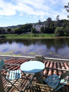 2 chaises et une table sur une terrasse à côté d'une rivière dans l'établissement The Riverview Loft, à Sainte-Foy-la-Grande