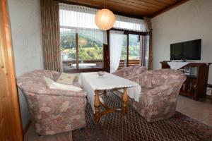 ein Wohnzimmer mit 2 Stühlen, einem Tisch und einem TV in der Unterkunft Haus Krick in Alpirsbach