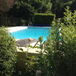 una piscina con 2 sillas y una flor en LA FERME D'AIGUROLLES, en Saint-Maur