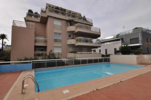 un bâtiment avec une piscine en face d'un bâtiment dans l'établissement Gorgeous one-bedroom apartment with terrace and sea view -StayInAntibes- Bijou Plage, à Antibes