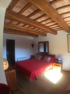 a bedroom with a red bed and a wooden ceiling at Es volca in Cadaqués