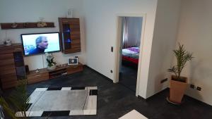 a living room with a flat screen tv and a bedroom at Gästehaus Ballmann 2 in Rockeskyll