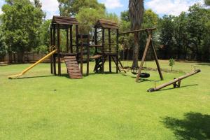 a playground with two swings and a slide at The Willow Tree Guesthouse in Klerksdorp