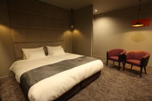 a bedroom with a large bed and two chairs at Hotel Banister Kyoto in Kyoto